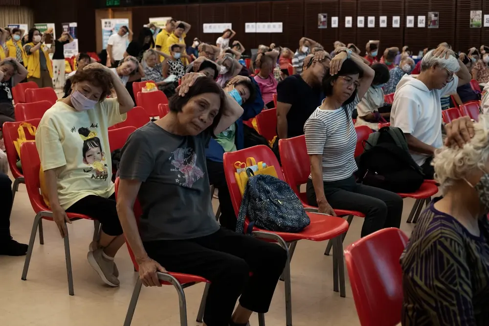 Participants following a seated neck stretch at an HKCCF community health event